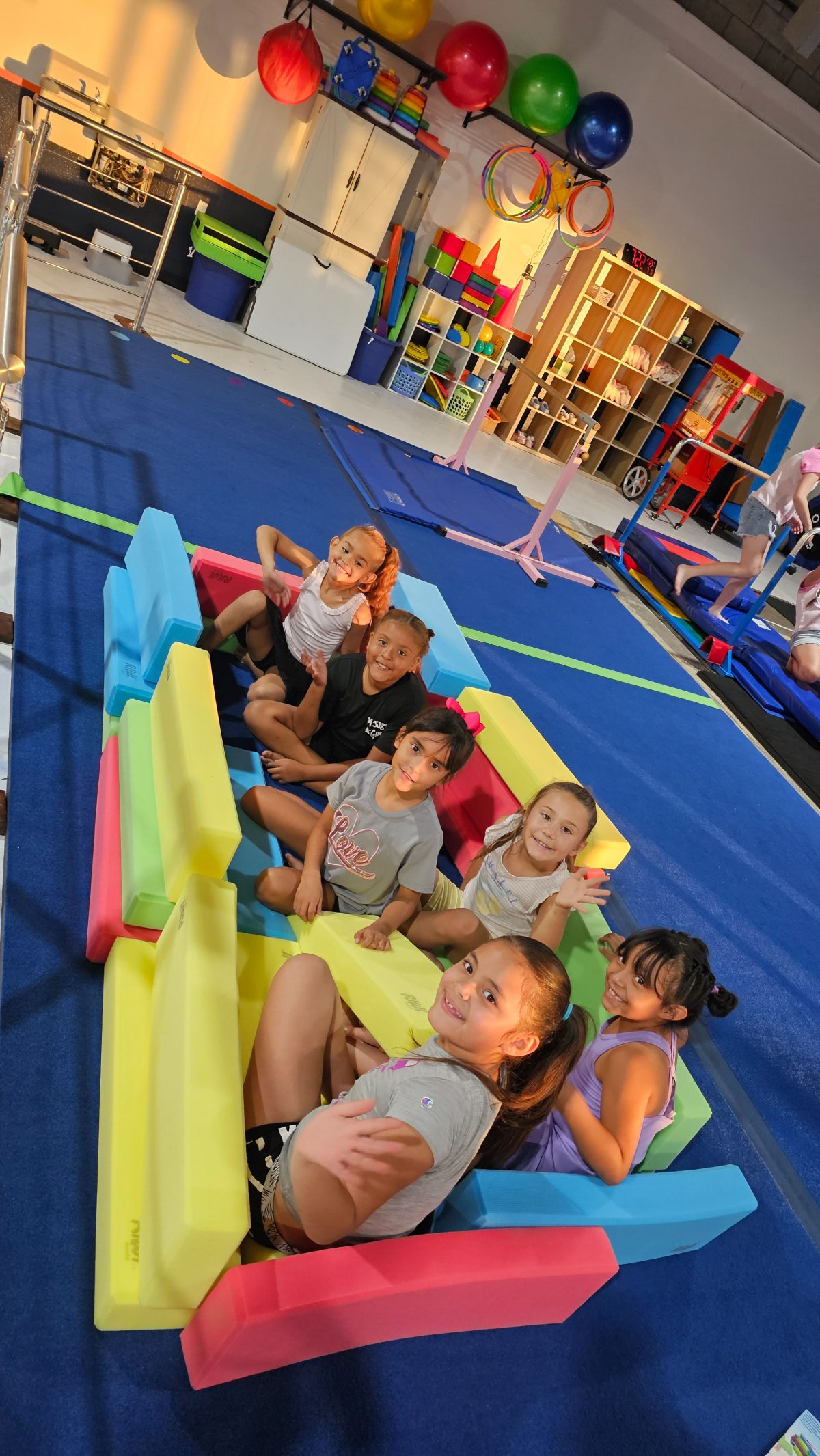 A group of kids smiling together on foam blocks at Kids Night Out